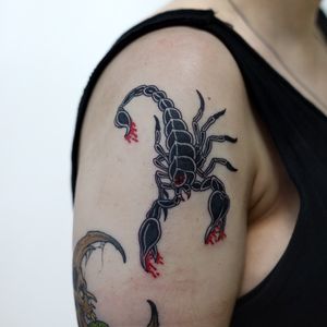 A bold and intricate blackwork scorpion tattoo on the upper arm, expertly crafted by the talented artist Leo Quintao.