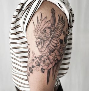 Stunning blackwork design on upper arm by tattoo artist Yasmin Clara, featuring a unique combination of an owl and flower motif.