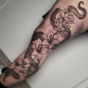 Get inked by Inkcognito with a striking blackwork design featuring a snake and flower on your knee. Unique and bold!
