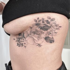 Elegant blackwork ribs tattoo featuring a beautiful illustrative flower by artist Yasmin Clara. Perfect combination of bold lines and delicate details.