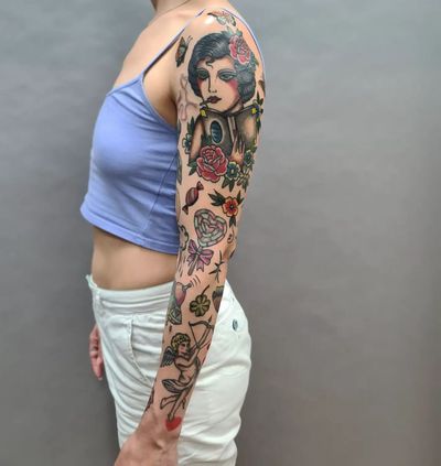 Beautiful traditional sleeve tattoo featuring flowers, hearts, angels, and women, expertly done by tattoo artist Liza Vettaa.