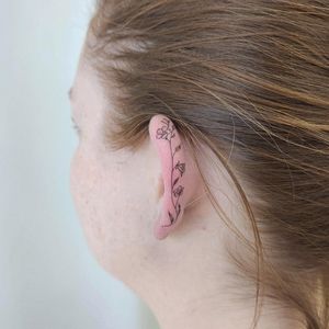 Elegant fine line flower tattoo designed to adorn your ear beautifully by Palena.