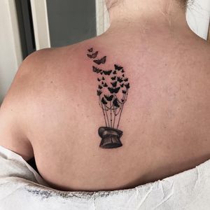 A stunning blackwork and fine line tattoo featuring a butterfly, hat, and balloon. Created by the talented artist Juli Liverinova.