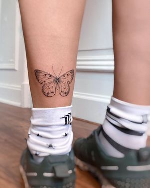 Elegant and delicate fine line butterfly illustration on lower leg by talented artist Irene Bogachuk.