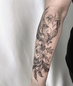 Stunning blackwork design on forearm featuring a beautiful phoenix and intricate flower by Palena.