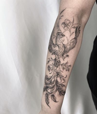 Stunning blackwork design on forearm featuring a beautiful phoenix and intricate flower by Palena.