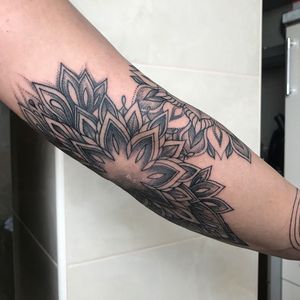 Blackwork and illustrative style arm tattoo showcasing a stunning mandala design created by the talented artist, Juli Liverinova.