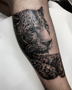 Get a fierce and detailed leopard tattoo on your lower leg by tattoo artist Juli Liverinova. Perfect for animal lovers and fans of blackwork style.