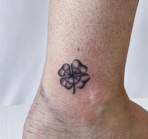 Elegant blackwork design by Jenna Jeep, featuring a detailed flower and leaf motif on the ankle.