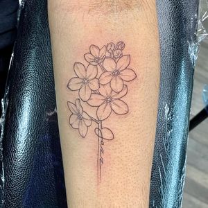 Small lettering and illustrative design on forearm featuring a flower, name, and quote.