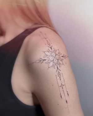 Elegant upper arm tattoo by Irene Bogachuk featuring a delicate flower motif and intricate geometric pattern design.