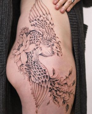 Unique upper leg tattoo by Sasha Sunshine featuring a stunning combination of a phoenix and flower in bold blackwork style.