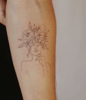 Beautiful forearm tattoo featuring a delicate fine line illustration of a woman and a flower, designed by Palena.