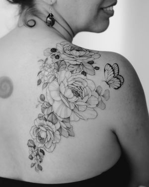 Elegant blackwork tattoo by Sasha Sunshine featuring a stunning butterfly and intricate flower design on the upper back.