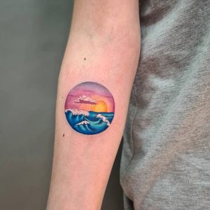 Captivating forearm tattoo by Liza Vettaa, featuring a stunning sea scene with sun and waves.