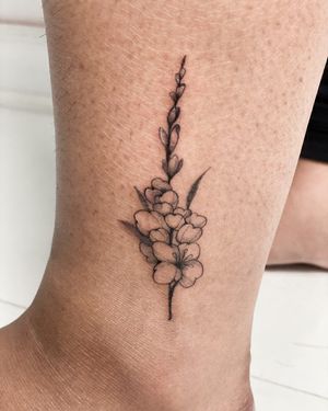 Adorn your ankle with a fine line flower tattoo by Yasmin Clara, adding a touch of beauty and elegance.