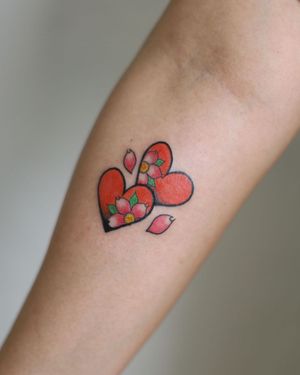 Vibrant cherry blossom and heart design by artist Leo Quintao, perfect for the forearm.
