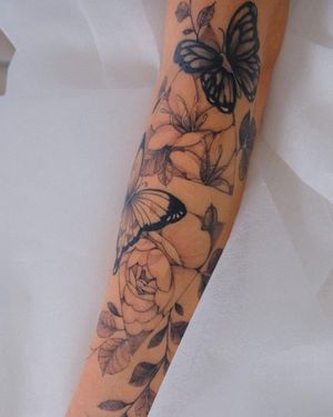 Illustrative blackwork tattoo featuring a butterfly and flower motif, by Yasmin Clara. Perfect for arm placement.