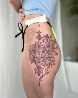 Stunning blackwork illustration by Yasmin Clara on upper leg, featuring a fierce lion, delicate flower, and intricate patterns.