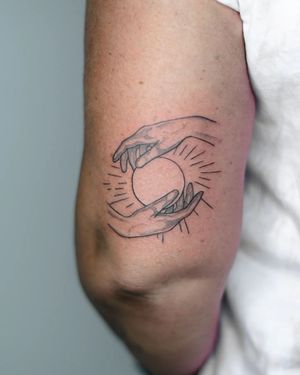 Adorn your upper arm with a beautiful fine line and illustrative tattoo of a sun and hand by the talented artist Kateryna Tytarenko.