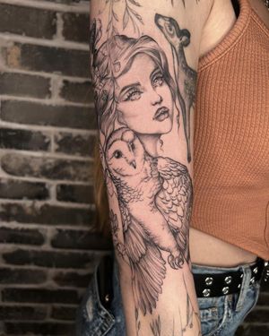 Palena's stunning blackwork tattoo on upper arm features a mystical owl, delicate flower, and mysterious woman.