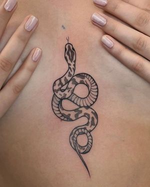 Bold blackwork and dotwork snake intertwined with intricate pattern on the sternum. Designed by Stasy Galz.
