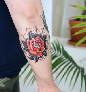 Get a stunning forearm tattoo by Liza Vettaa, featuring a beautiful flower intertwined with a classic spider web design. Perfect blend of traditional and illustrative styles.