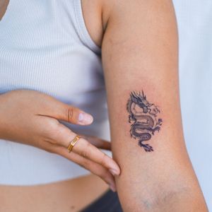 Stunning illustrative dragon tattoo on upper arm, masterfully inked by the talented artist Yasmin Clara.
