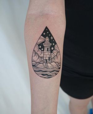 A stunning illustrative lighthouse surrounded by powerful waves, expertly done by tattoo artist Nicole Ksiazek on the forearm.