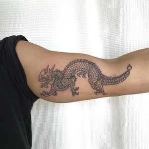 Capture the power and grace of a Japanese dragon with this fine line illustrative tattoo by Leo Quintao on your upper arm.