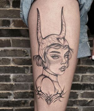A captivating blackwork tattoo on upper leg by Palena, featuring a woman's face with horns and a helmet surrounded by thorns and intricate patterns.