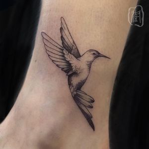 Adorn your ankle with a stunning blackwork hummingbird tattoo by Cerf. A symbol of grace and beauty.