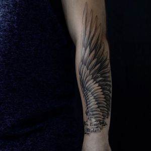 Nicole Histon's blackwork forearm tattoo features an illustrative wing design and empowering quote.