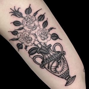 Get inked with a stunning black-and-gray flower vase design on your arm by Letitia Mortimer. Embrace elegance and beauty.
