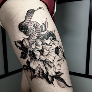 Get a stunning illustrative tattoo on your upper leg by artist Nicole Histon. The design features a beautiful snake intertwined with a delicate flower.