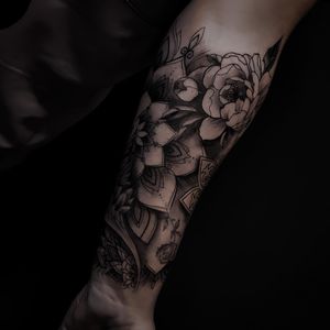 Elegant forearm tattoo combining intricate patterns and floral elements in unique blackwork style by renowned artist Nicole Histon.
