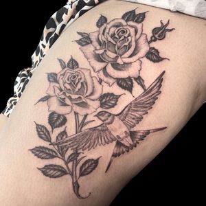 Elegant black and gray upper leg tattoo featuring a delicate bird and flower motif, by Letitia Mortimer.