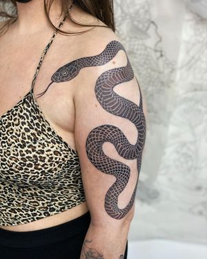 A striking black and gray snake tattoo on the upper arm, expertly crafted by artist Sophie Rose Hunter.