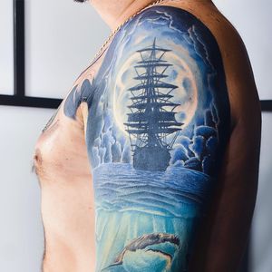 Illustrative upper arm tattoo featuring a mesmerizing blend of sea, moon, shark, and ship elements by artist Nicole Histon.