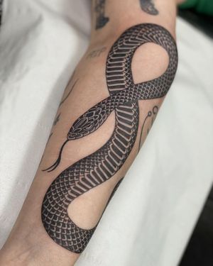 A stunning black and gray traditional style snake tattoo on the forearm, expertly done by tattoo artist Sophie Rose Hunter.