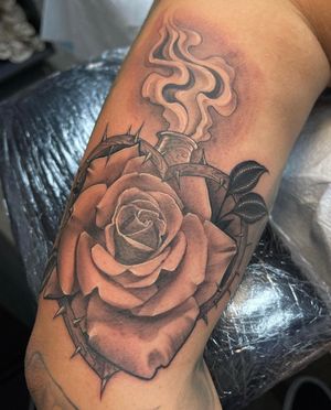 Experience the beauty of blackwork and realism with this illustrative tattoo of a flower tangled in thorns on your upper arm by talented artist Lokey.