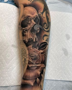 Beautiful illustrative tattoo on lower leg by Lokey, featuring a skull and flower motif in bold blackwork style.