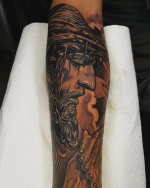 Embrace faith with this intricate blackwork tattoo by Lokey. Featuring a powerful illustration of Jesus, perfect for the forearm.