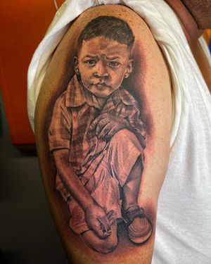 A striking blackwork tattoo of a boy in detailed realism style on the upper arm, by Lokey.