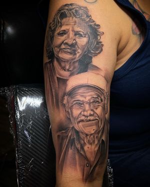 An illustrative tattoo of a man and woman wearing caps, beautifully crafted in blackwork style by artist Lokey on the upper arm.