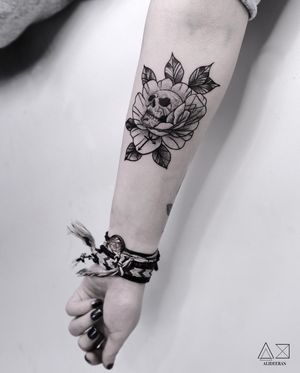 Beautiful blackwork tattoo featuring an illustrative skull and flower design by Ali Deeran. Perfect for forearm placement.