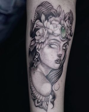 Adorn your forearm with a striking blackwork tattoo featuring a beautiful woman, elegant flowers, a sparkling jewel, and dangling earrings.