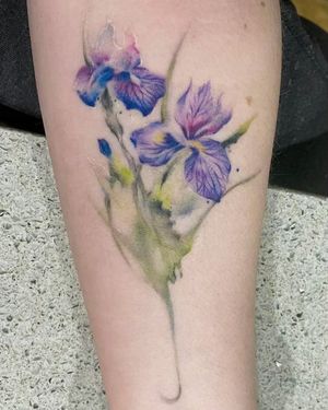 Vibrant illustrative flower tattoo on forearm by Mengni Yang. A beautiful and unique watercolor style design.
