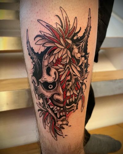Beautiful illustrative tattoo featuring a Japanese flower and Hannya mask design on the lower leg by Tom Cobra.