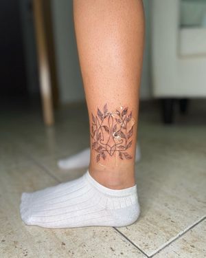 Graceful and delicate leaf design on the ankle, beautifully executed in fine line illustrative style by artist Alina Ivenko.